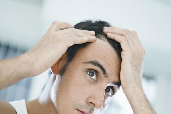 Tricopigmentación - Hombre de cabello negro aprecia un notable aumento de su densidad capilar frente al espejo