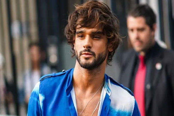 Cortes de pelo largo para hombre - Joven con estilo desenfadado y camisa en azul degradado luce un look surfero para salir a la calle