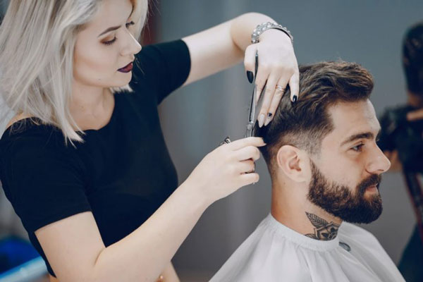 Estilista recorta las puntas de un cliente para fortalecer y estimular el crecimiento del cabello