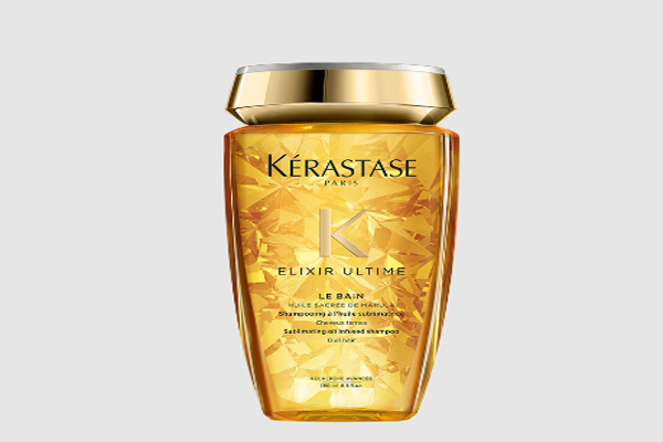 Presentación del lujo del Champú Sublimador Le Bain Elixir Ultime de Kérastase con destellos dorados que asoman como realzará el brillo de tu cabello