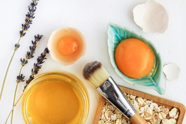 Brocha, huevos y aceite de oliva sobre la mesa como ingredientes esenciales para potenciar la nutrición del pelo