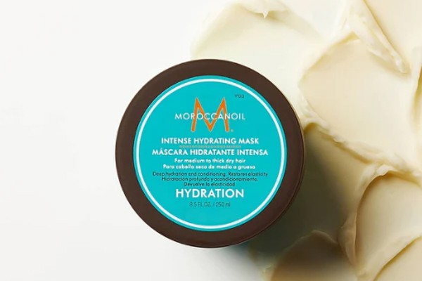 Presentación de la mascarilla intensiva hidratante de Moroccanoil con parte de su cremoso contenido alrededor