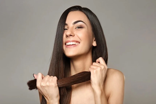 Aceite de argán - Chica de cabello castaño se muestra orgullosa con la fuerza y el grosor de su pelo
