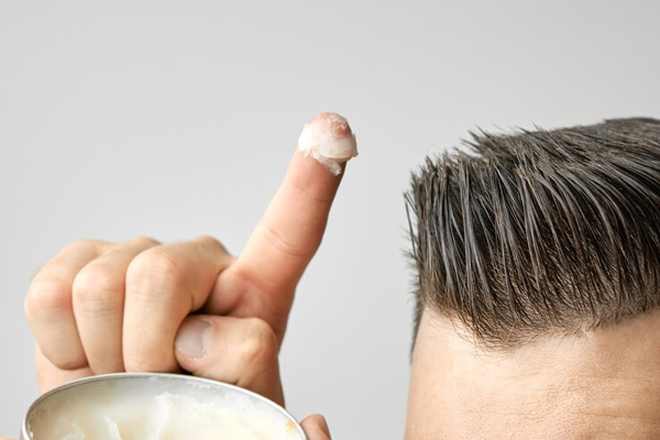 Tips para hacer crecer el pelo - Hombre toma un poco de gel capilar en su dedo para darle forma a su pelo con más facilidad