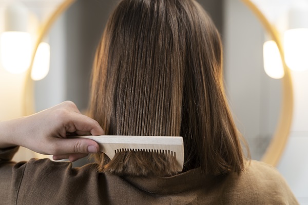 Mujer peinando su cabello liso gracias al tratamiento de hidratación profunda