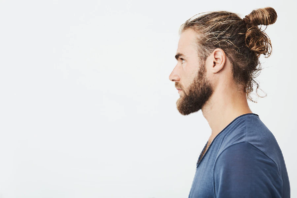 cortes de pelo largo para hombre - Chico de perfil lleva el cabello recogido para realzar su estilo
