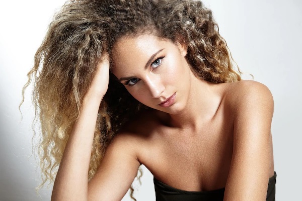 Pelo seco - Mujer posando con su cabello rizado, el cual se observa seco y sin brillo