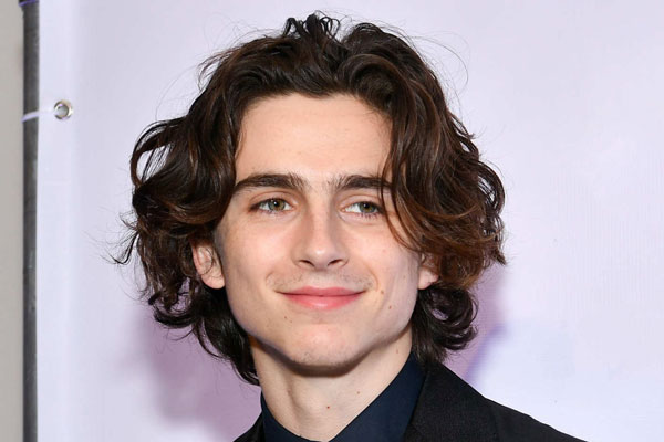 Cortes de pelo largo para hombre - Timothée Chalamet sonríe ante las cámaras con su fresca y abundante melena
