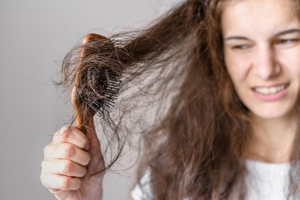 Pelo seco - Mujer intentando peinar su cabello, el cual tiene muchos nudos por estar reseco