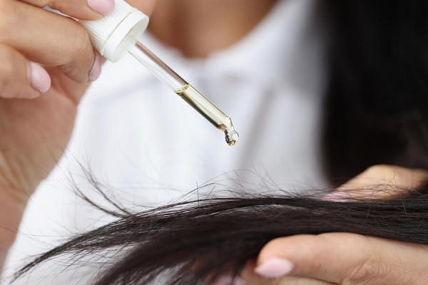 Mujer aplicando aceite de castor en su cabello para revitalizar y fortalecerlo