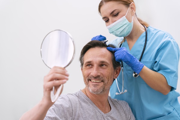 Doctora revisando los avances del paciente que recibió un trasplante de cabello, el cual está muy feliz con los resultados