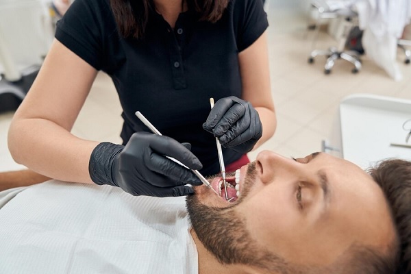 caries y calvicie - Paciente abre la boca para que el dentista revise el estado en el que se encuentran sus dientes