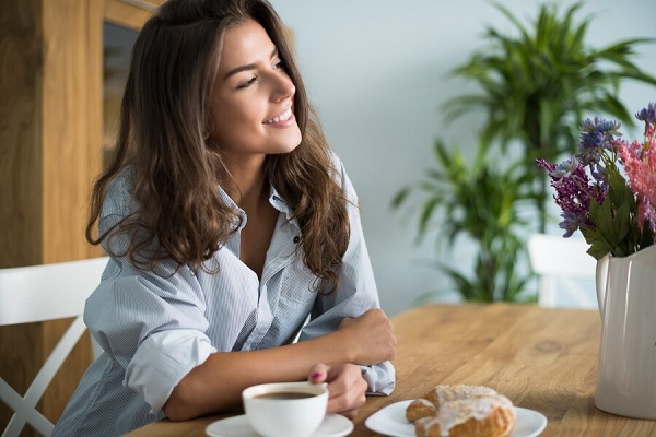 densidad del pelo fino - mujer joven de pelo largo sonriendo mientras toma el desayuno