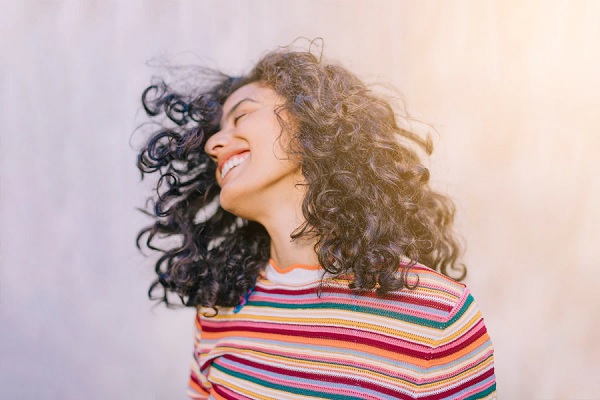 mujer blanco con la melena rizada y un jersey a rayas de colores bajo el sol