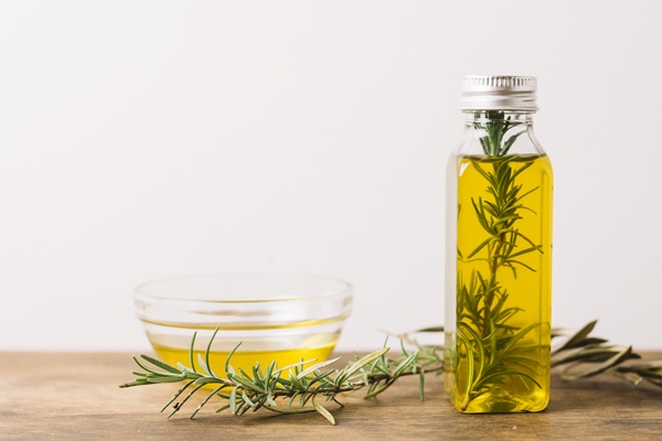 Recipientes con aceite de quina y planta de romero para hacer el tratamiento capilar desde casa