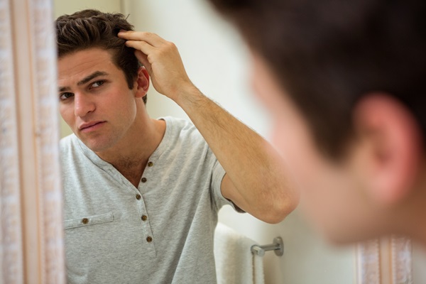 Testosterona y caída del cabello - Hombre observando que empieza a perder cabello por el consumo de suplementos de hormonas y testosterona