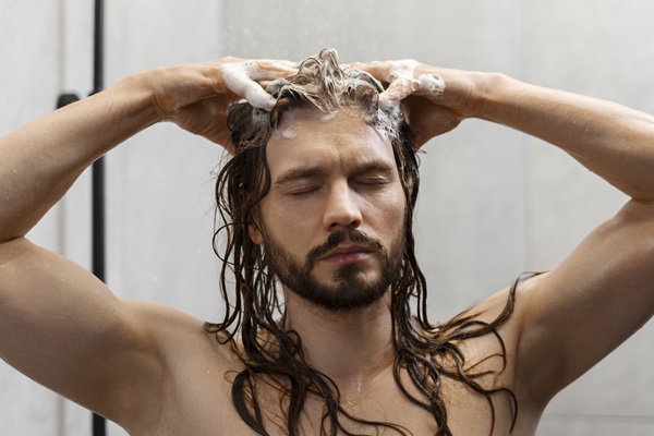 Exfoliantes capilares - Hombre dando masajes a su cuero cabelludo mientras lo exfolia, para estimular la circulación sanguínea y el crecimiento del cabello