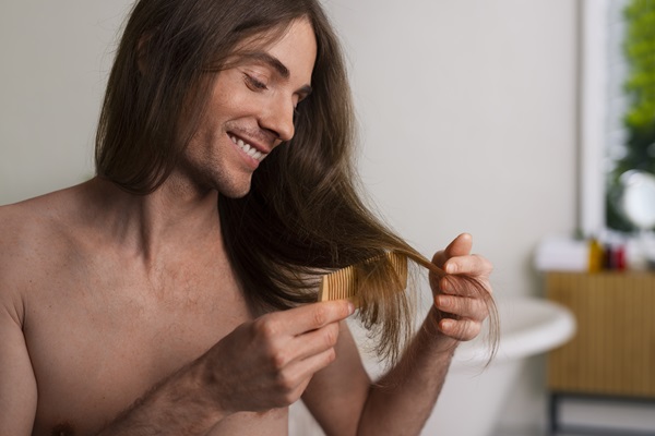 Hombre cepillando su cabello liso luego del tratamiento, luciendo muy sedoso y brillante