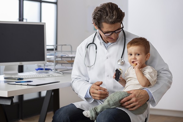 Pediatra evaluando el cuero cabelludo de un bebé, para diagnosticar si presenta alguna lesión cutánea