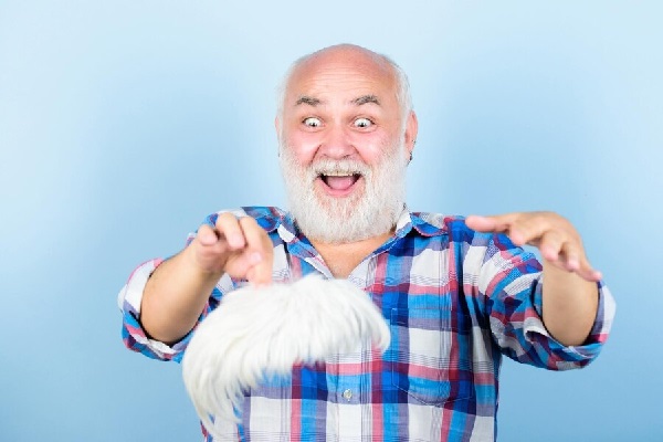 Prótesis capilar - Hombre sosteniendo una prótesis capilar que lo ayuda a combatir la alopecia, simulando la apariencia de su cabello natural