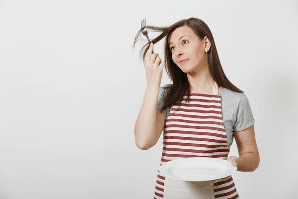 Tricofagia - Mujer con delantal enrolla su cabello en un tenedor