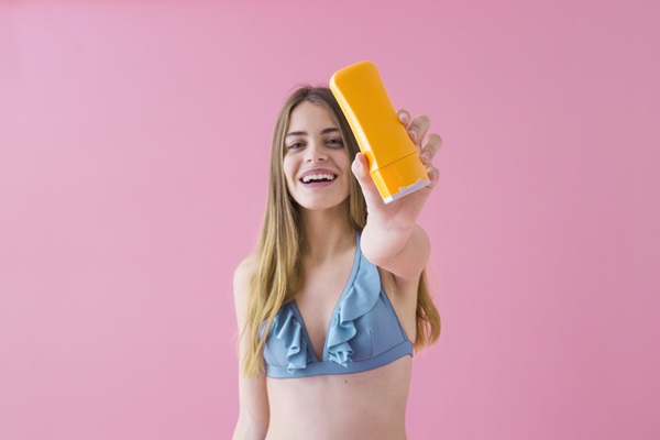 Mujer enseñando el producto capilar que utiliza, para proteger el cabello de los daños que ocasionan los rayos UV durante el verano