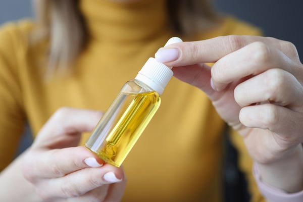 Mujer sosteniendo un recipiente con aceite de castor, el cual aplica en el cabello para favorecer un crecimiento más rápido