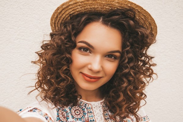 Hermosa modelo sonriente con peinado afro rizos vestido con vestido blanco hípster de verano