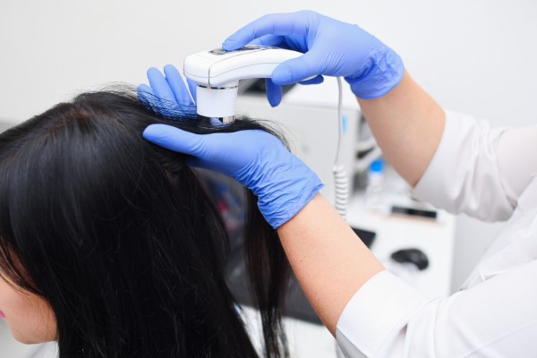 densidad del cabello rizado - mujer en la consulta de la tricóloga midiendo la densidad de su cabello