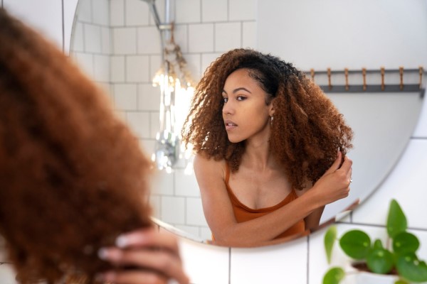 mujer afroamericana delante del espejo revisando su melena rizada