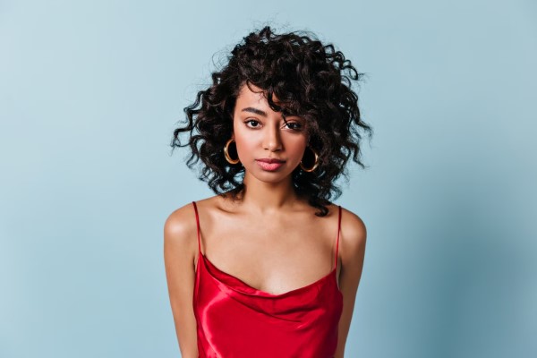 densidad del cabello rizado - Vista frontal de una elegante mujer con la melena rizada con un vestido de tirantes rojo