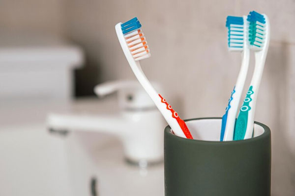 Vaso con cepillo de dientes para el aseo personal en el baño 