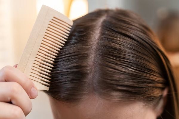 Vinagre de manzana - Joven cepilla su cabello con un peine de madera para mantenerlo libre de nudos 