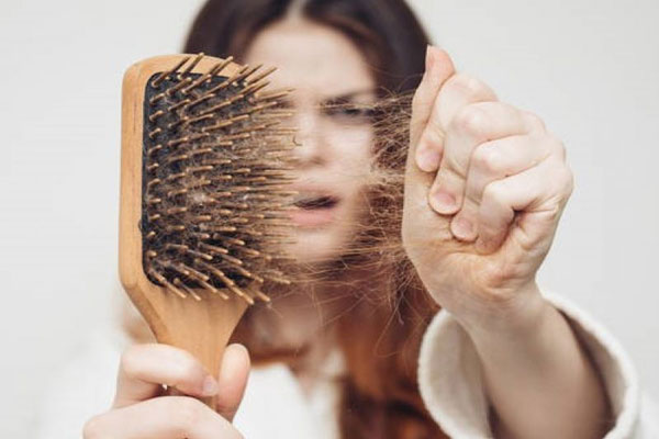 Fases del crecimiento del pelo - Joven de tez blanca extrae abundantes mechones de pelo tras cepillar su cabello