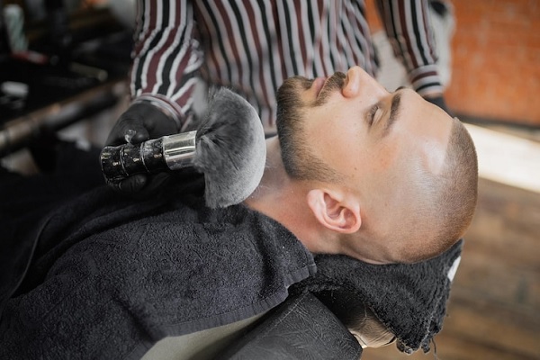 Cuidar la barba - Barbero cortando el vello facial de un hombre, para moldear un estilo acorde a sus rasgos físicos