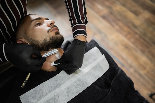 Barbero cortando el vello facial de un hombre, para darle un estilo elegante y atractivo que vaya acorde a sus rasgos físicos