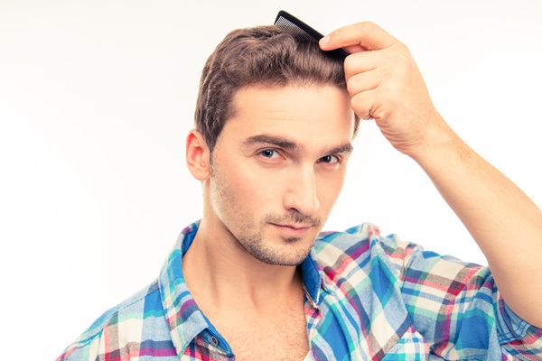 Hombre peinando su cabello de manera suave, para no jalar los folículos pilosos durante la recuperación del implante