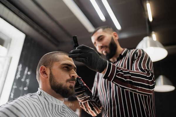 Pelo tras injerto capilar - Barbero realizando un corte de cabello con mucho cuidado a un cliente, el cual está en proceso de recuperación de un trasplante capilar