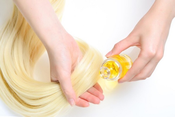 Reparar el cabello dañado - Mujer aplicando una mascarilla de aceite de oliva en el cabello, para hidratar las hebras capilares y sellar las cutículas