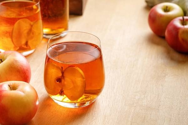 Vinagre de manzana - Jugo de manzana fermentado es servido en un vaso de vidrio para su procesamiento en serie 