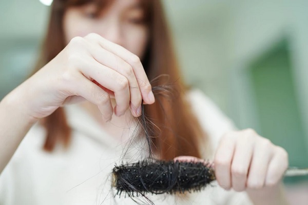 Alopecia androgénica en mujeres - Mujer observando la cantidad de cabello que pierde al peinarse, debido al debilitamiento de las hebras capilares