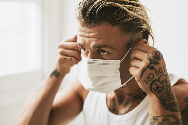 Hombre colocándose una mascarilla para no propagar la enfermedad que padece