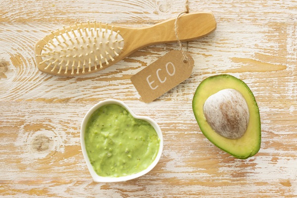 Reparar el cabello dañado - Imagen de un cepillo junto a un recipiente con la mascarilla capilar de miel, huevo y aguacate, la cual ayuda a hidratar y nutrir el pelo