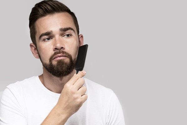 Cuidar la barba - Hombre peinando su barba con un cepillo suave, lo cual favorece el crecimiento del vello en una dirección fija