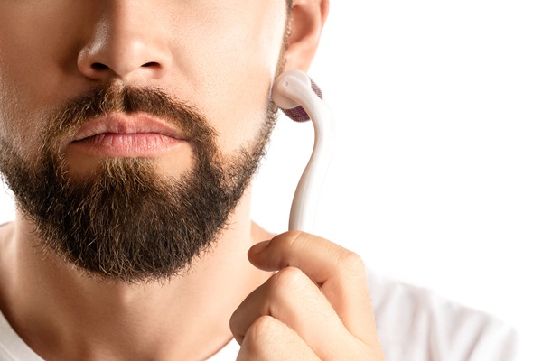Hombre pasando un rodillo sobre su rostro, para estimular el crecimiento del vello facial