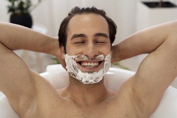Cuidar la barba - Hombre lavando su barba con un jabón especial mientras se ducha, para mantener la higiene de los vellos faciales