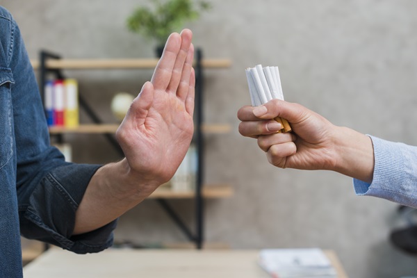 Hombre rechazando consumir cigarrillos, ya que fumar afecta la recuperación del injerto de cabello