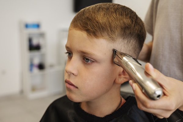 Estilista cortando el cabello de un jóven, para crear un look moderno