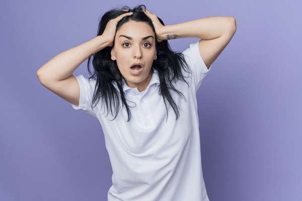 Alopecia androgénica en mujeres - Mujer sujetando su cabeza en señal de asombro, debido a las consecuencias de la alopecia androgénica