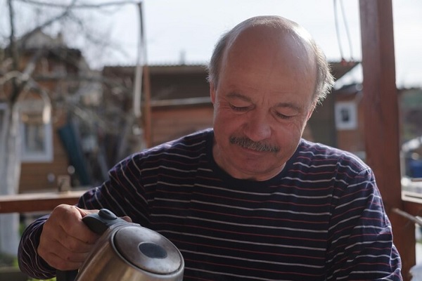 Verano y calvicie - Hombre con alopecia sirviéndose una bebida para mantenerse hidratado durante el verano